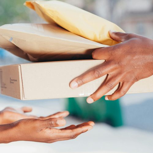 pexels-photo-6868618-6868618 Close-up image of hands exchanging packages outdoors. Represents delivery and shipping services.